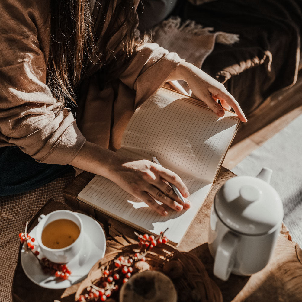 Woman writing in her journal for sustainable New Years Goals.