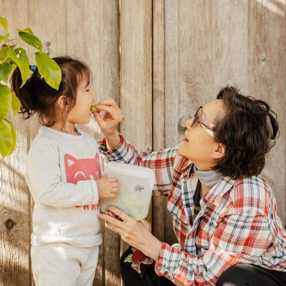 Grandma feeding toddler grapes in small Silicone Zip Sealer.