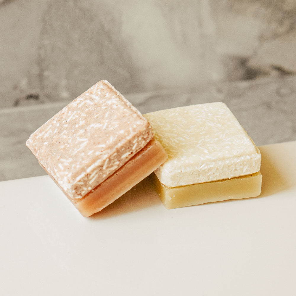 Shampoo and conditioner bars on bathroom tub.