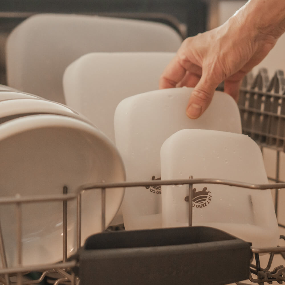 Hand grabbing Small Silicone Zip Sealer from the dishwasher.