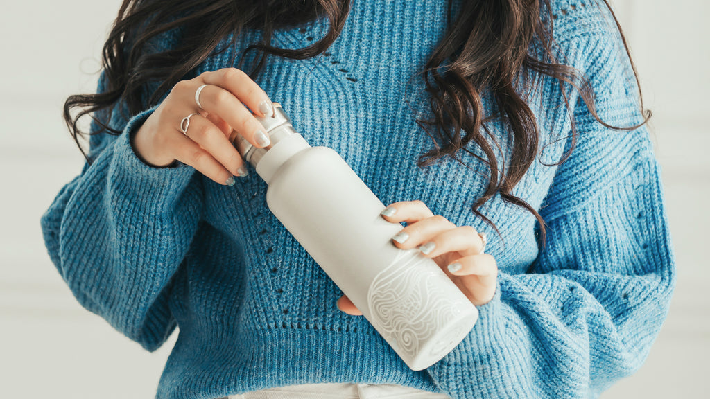 Woman holding zero-waste water bottle.