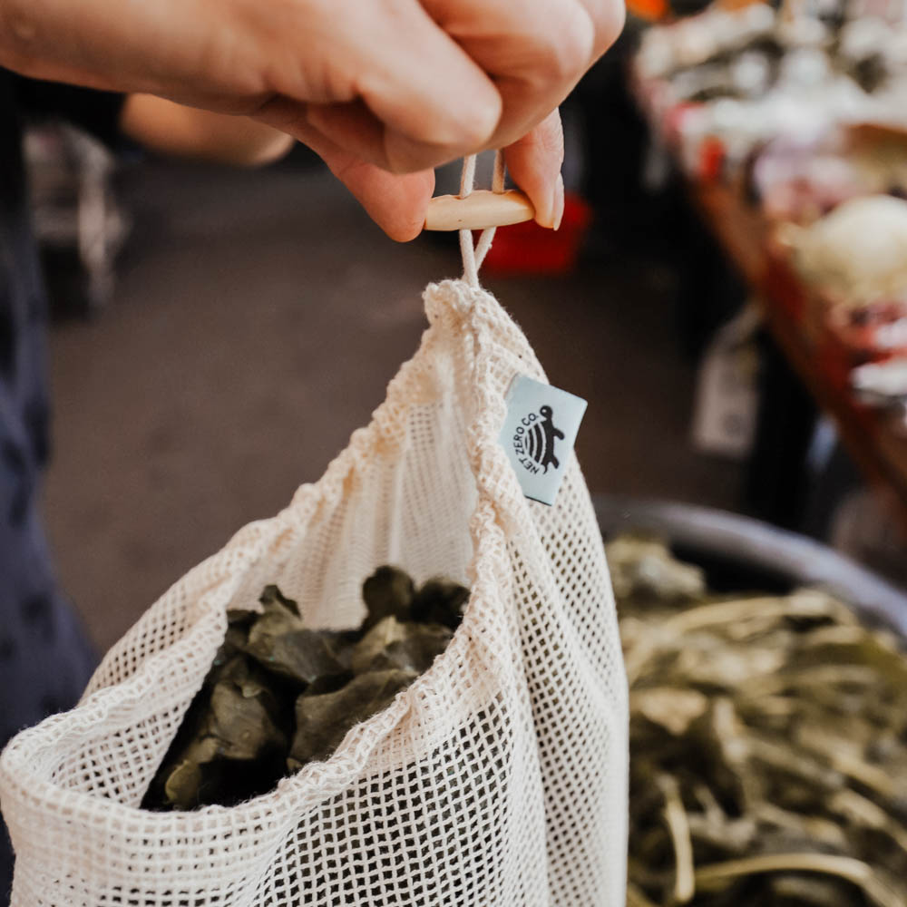 Hand Closing Wood Toggle On Net Zero Produce Bag At The Farmer's Market