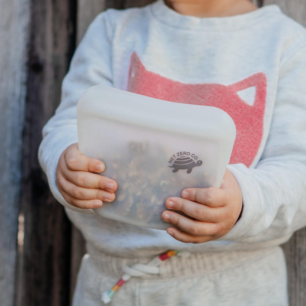 Toddler holding walnut as snack inside small Silicone Zip Sealer.