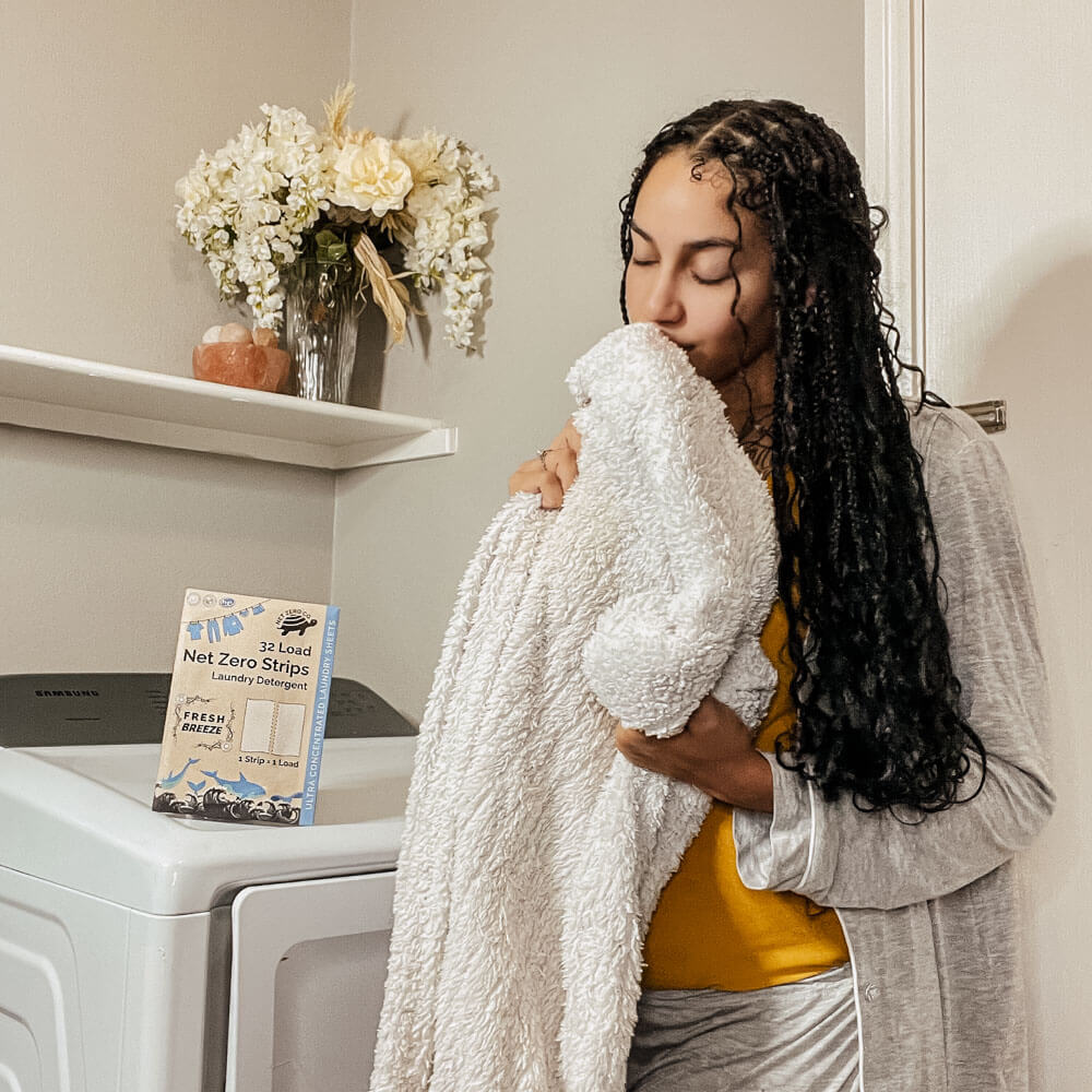 Woman smelling fresh laundry by Net Zero Co. laundry strips.